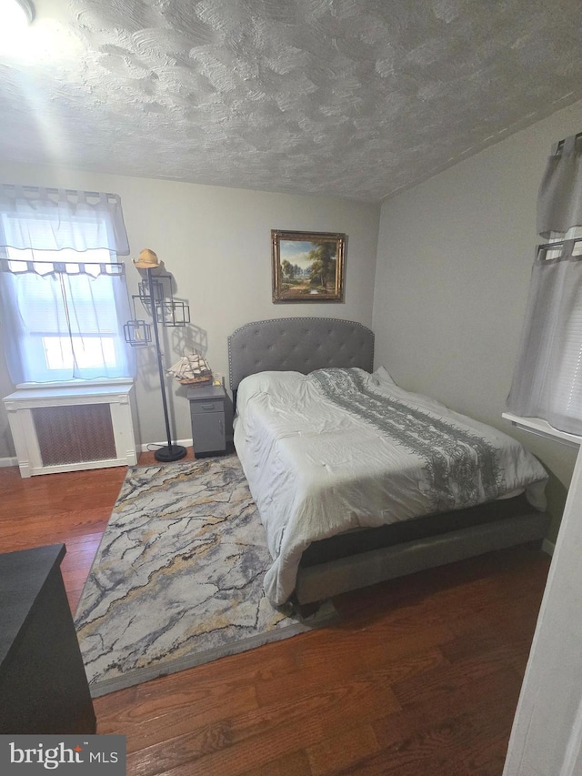 bedroom with a textured ceiling, baseboards, and wood finished floors