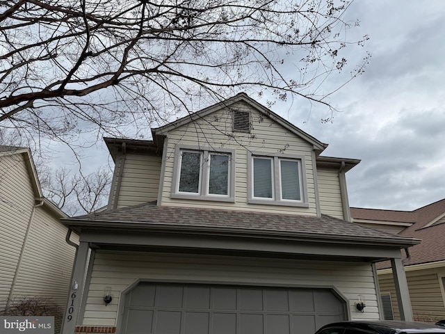 view of side of home featuring a garage and a shingled roof