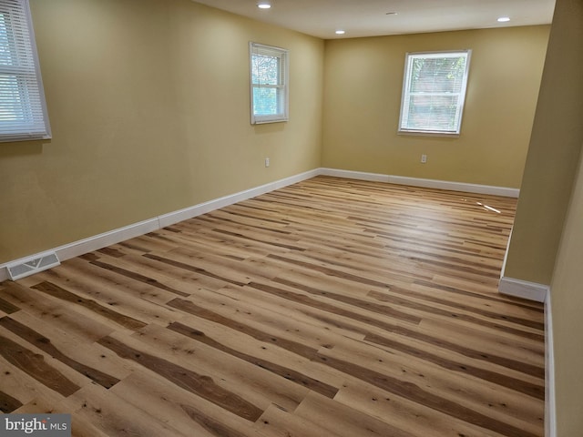 empty room with plenty of natural light, wood finished floors, visible vents, and recessed lighting