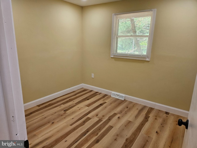 empty room featuring light wood finished floors, baseboards, and visible vents