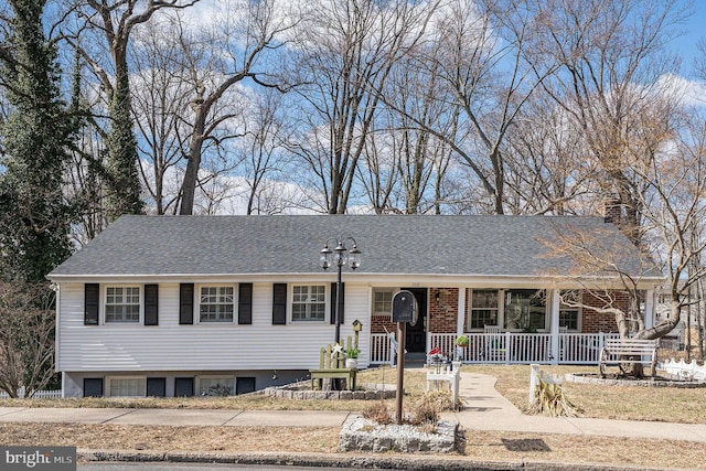 view of front facade featuring brick siding, covered porch, a chimney, and roof with shingles