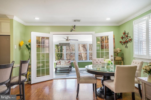 dining space featuring crown molding, wood finished floors, and visible vents