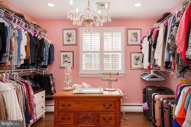 spacious closet featuring visible vents, wood finished floors, a baseboard heating unit, and a chandelier