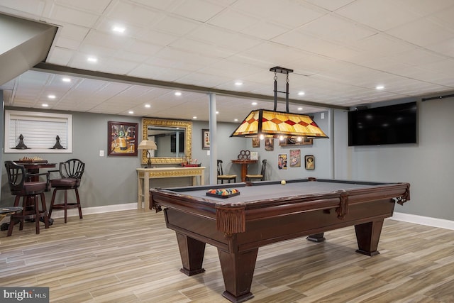 game room with light wood finished floors, a dry bar, and baseboards