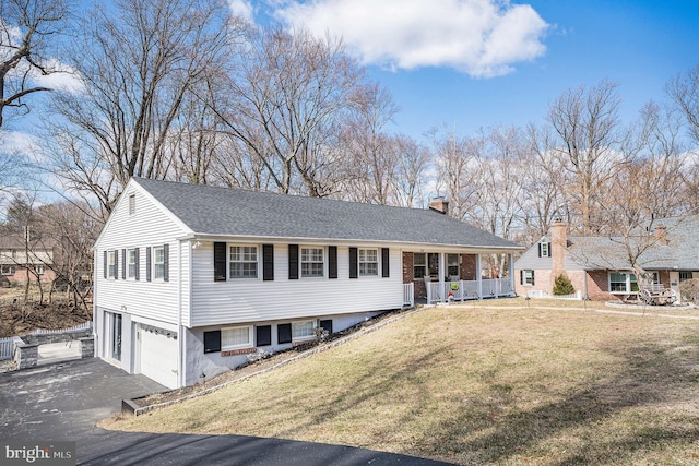 view of front of house with a front lawn, driveway, covered porch, a garage, and a chimney