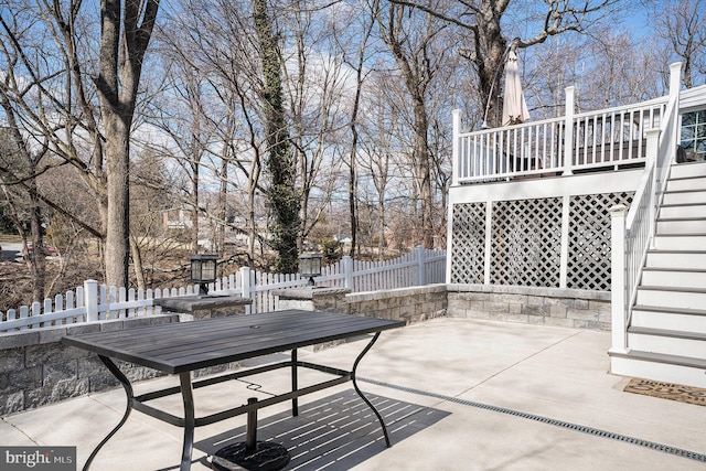 view of patio with stairway, outdoor dining area, a deck, and fence