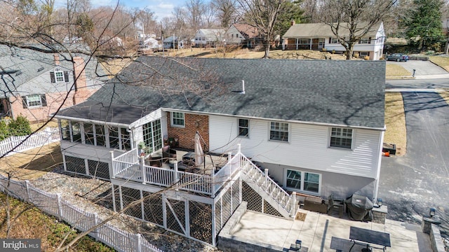 rear view of house with a sunroom, fence, a shingled roof, a wooden deck, and stairs