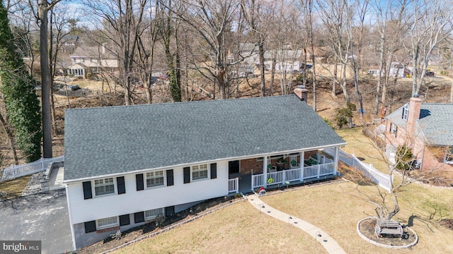 view of front of house featuring a shingled roof, a front lawn, fence, a porch, and driveway