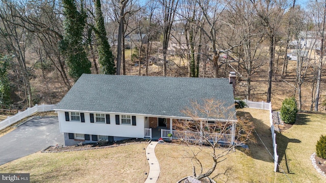 view of front of home with a porch, a chimney, a front lawn, and roof with shingles