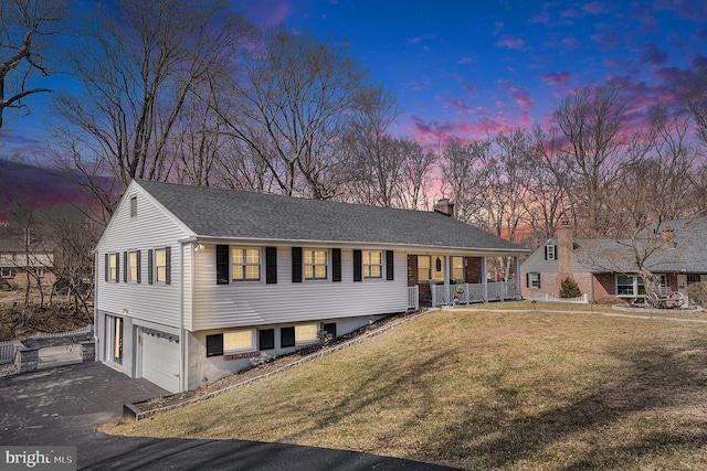 view of front of home with aphalt driveway, a porch, a front yard, a chimney, and a garage