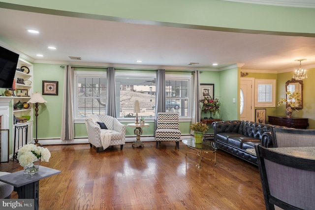 living area with a baseboard heating unit, ornamental molding, recessed lighting, a fireplace, and wood finished floors