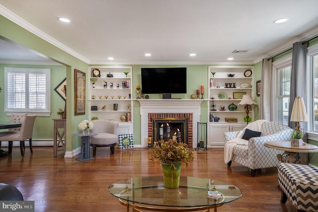 living room with a wealth of natural light, visible vents, crown molding, and wood finished floors