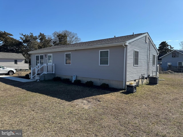 view of front facade with a front yard, fence, and central air condition unit