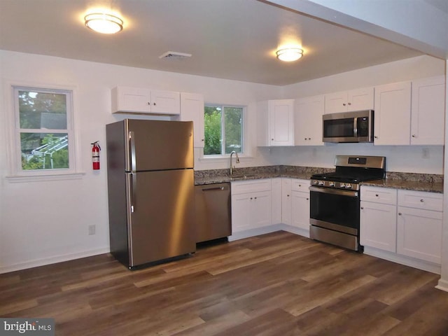 kitchen with appliances with stainless steel finishes, dark wood-style flooring, white cabinets, and a sink