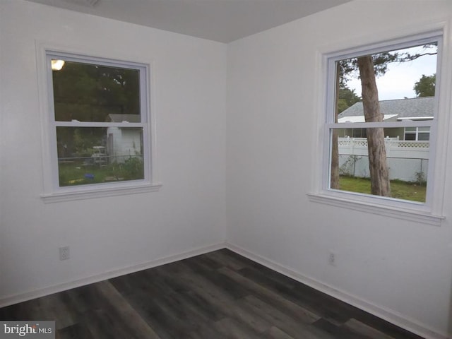 empty room with dark wood finished floors and baseboards