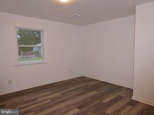 spare room featuring baseboards, visible vents, and dark wood-style flooring