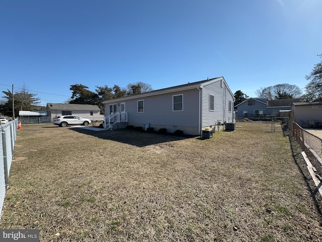 view of front facade with central AC, a front yard, and fence