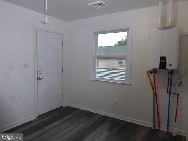 interior space featuring dark wood-type flooring, tankless water heater, visible vents, and baseboards