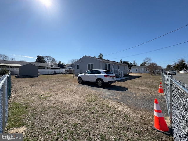 view of yard featuring a storage unit, an outdoor structure, fence, and a residential view