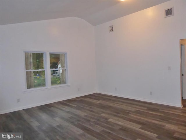 unfurnished room with vaulted ceiling, dark wood finished floors, visible vents, and baseboards