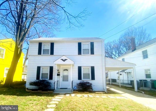 colonial home featuring an attached carport, driveway, and a front yard