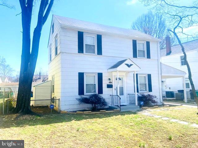 colonial inspired home with central AC unit, a front lawn, and fence