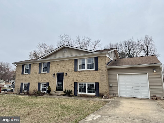 split foyer home featuring a garage, driveway, brick siding, and a front lawn