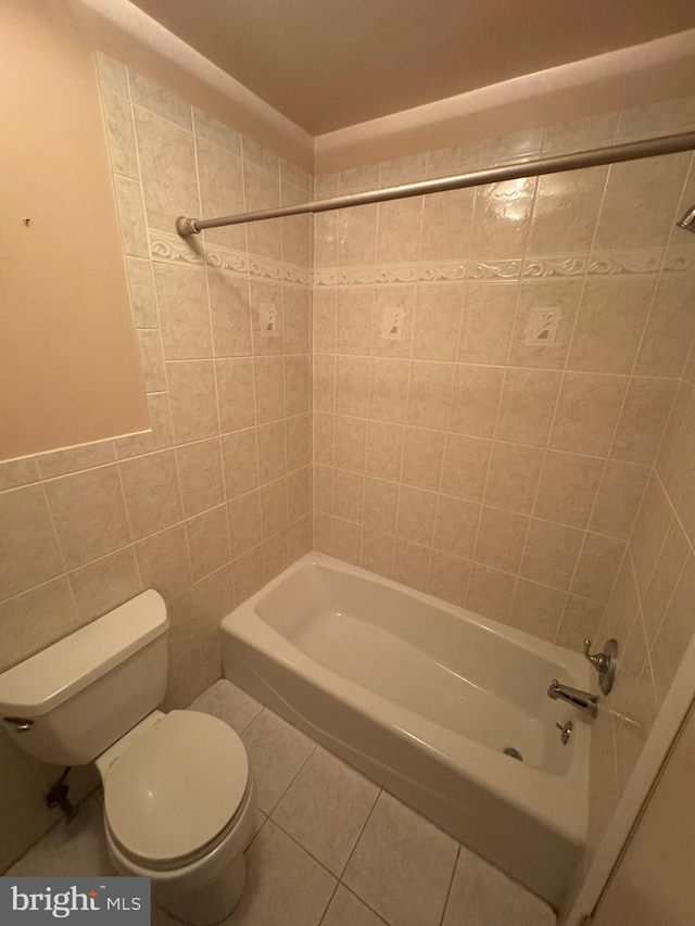 bathroom with tile patterned flooring, tile walls, toilet, and tub / shower combination