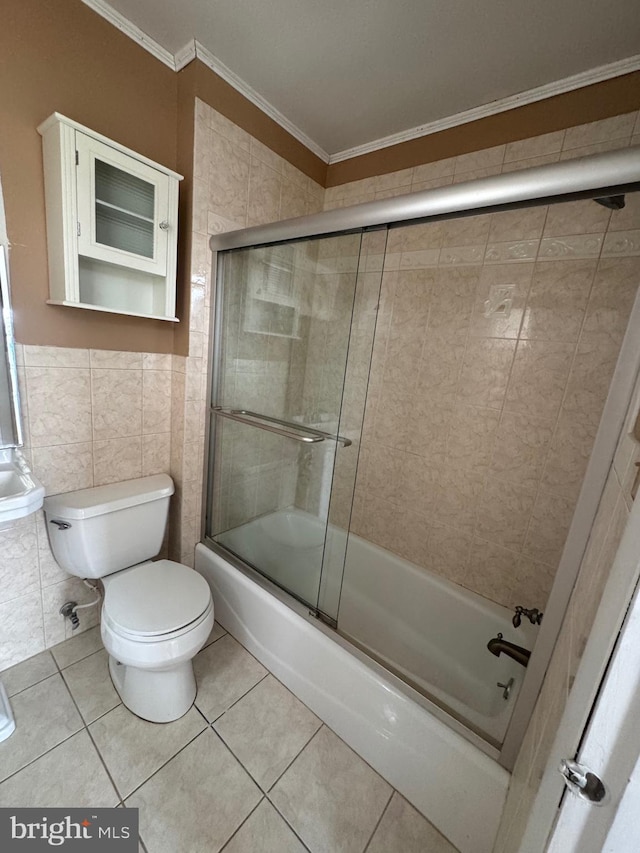 full bath with tile patterned flooring, crown molding, toilet, shower / bath combination with glass door, and tile walls