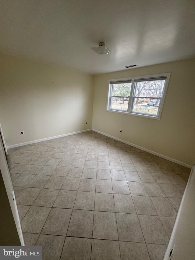 tiled empty room featuring visible vents and baseboards