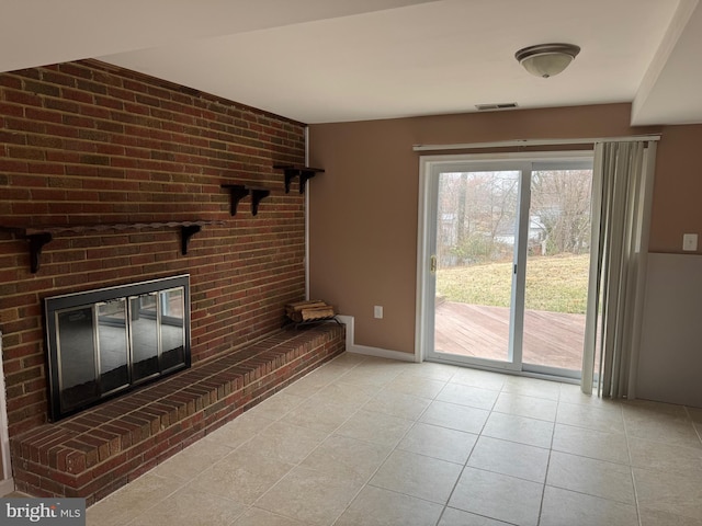 unfurnished living room with light tile patterned floors, visible vents, baseboards, and a brick fireplace