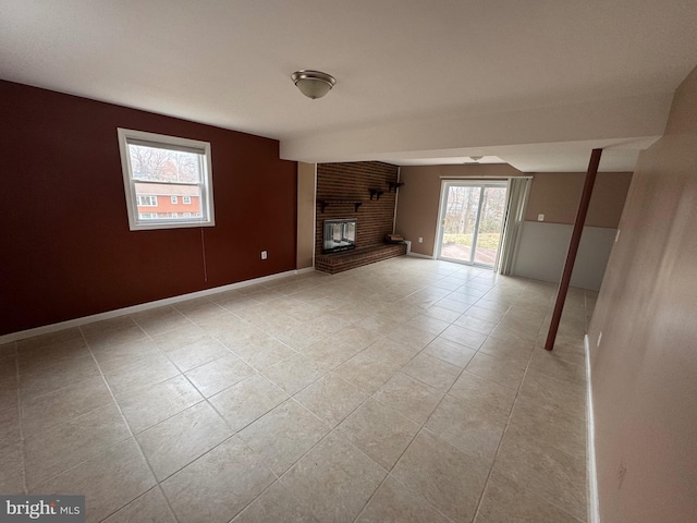 unfurnished living room with light tile patterned floors, a brick fireplace, and baseboards