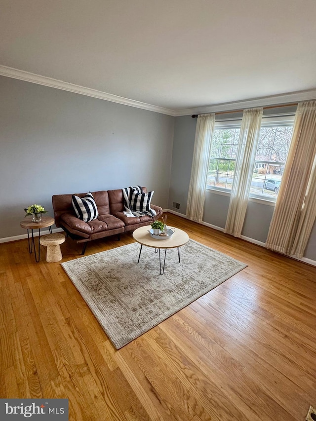 unfurnished living room featuring visible vents, baseboards, wood finished floors, and ornamental molding