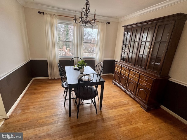 dining area featuring light wood finished floors, a notable chandelier, baseboards, and ornamental molding