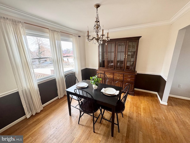 dining space with baseboards, light wood-style floors, an inviting chandelier, and ornamental molding