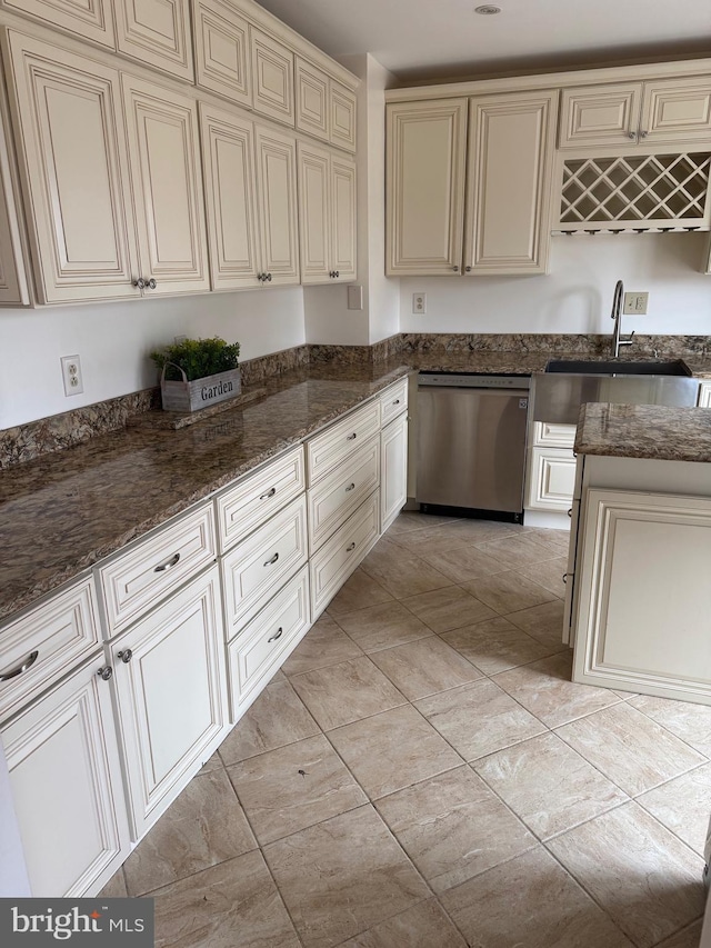 kitchen with cream cabinetry, dishwasher, dark stone counters, and a sink