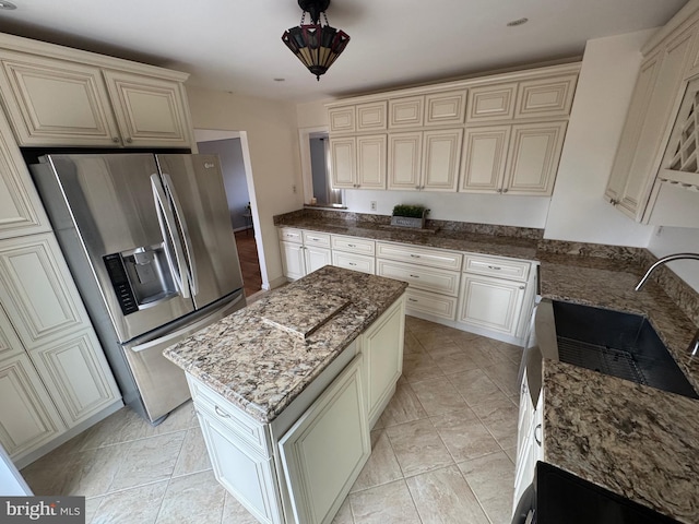 kitchen featuring a kitchen island, dark stone countertops, cream cabinets, and stainless steel fridge with ice dispenser