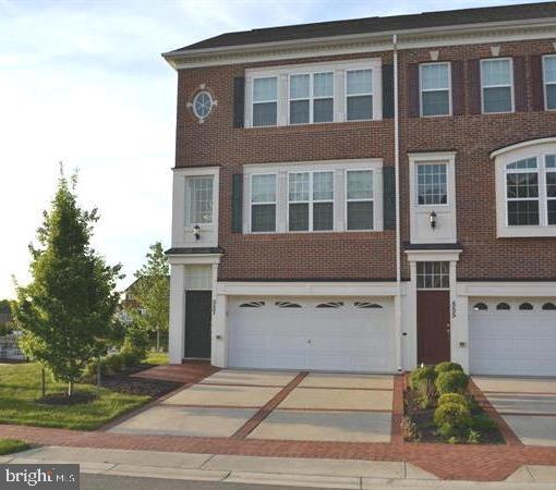 multi unit property featuring a garage, driveway, and brick siding