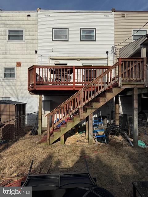 rear view of house featuring stairway, a wooden deck, and fence