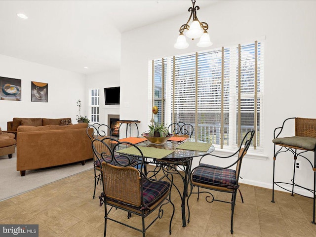 dining space with an inviting chandelier, baseboards, and a lit fireplace