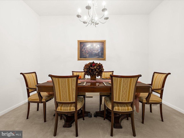 dining room featuring a notable chandelier, light colored carpet, and baseboards