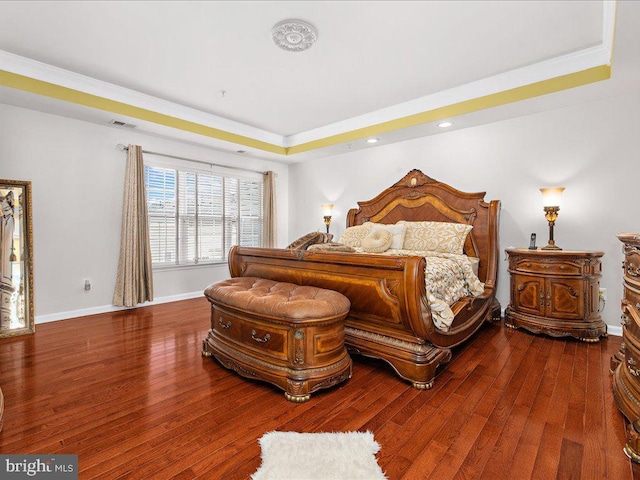 bedroom with hardwood / wood-style floors, a raised ceiling, visible vents, and baseboards