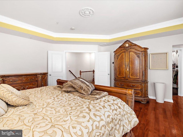 bedroom featuring dark wood finished floors, crown molding, and baseboards