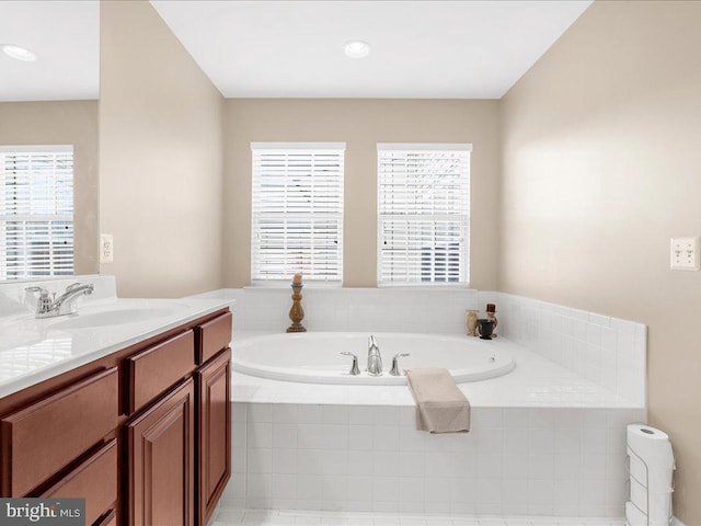 full bath with a wealth of natural light, a bath, and vanity