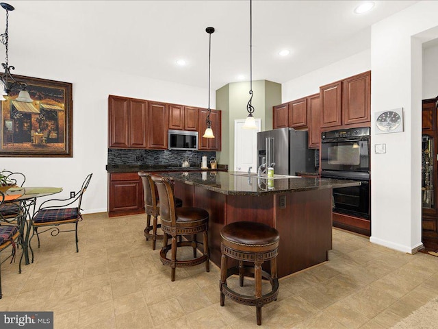 kitchen featuring decorative light fixtures, a kitchen island, backsplash, appliances with stainless steel finishes, and a breakfast bar area