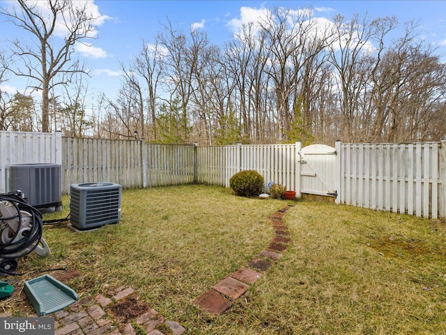 view of yard featuring central air condition unit, a fenced backyard, and a gate