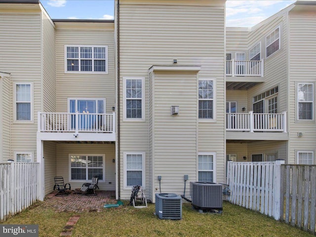 rear view of house with cooling unit and fence