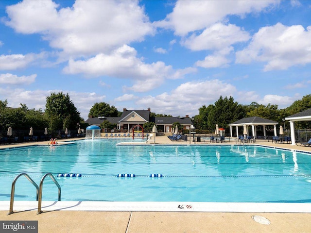 community pool with a gazebo, a patio area, and fence