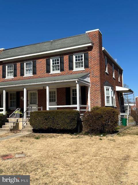 multi unit property with a porch and brick siding