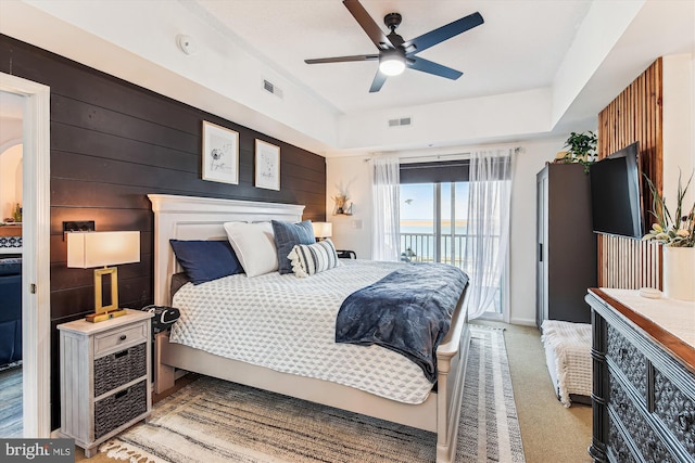 bedroom featuring access to exterior, visible vents, carpet flooring, and a raised ceiling